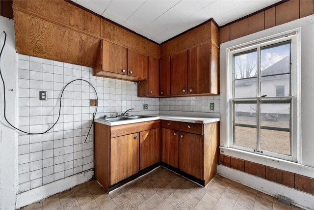 kitchen with brown cabinetry, light countertops, a sink, and tasteful backsplash