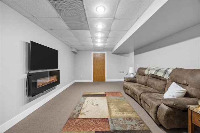 living area featuring a paneled ceiling, visible vents, baseboards, carpet, and a glass covered fireplace