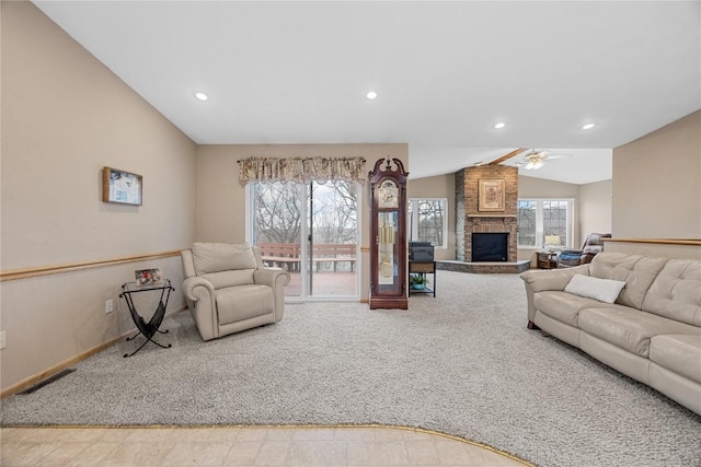 living area featuring a wealth of natural light, a large fireplace, carpet flooring, and vaulted ceiling