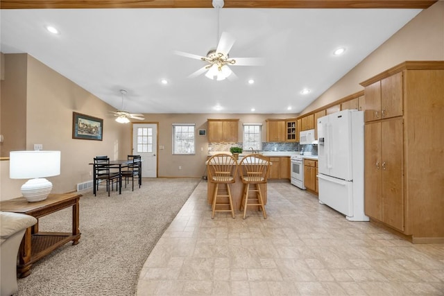 kitchen featuring light carpet, white appliances, a ceiling fan, lofted ceiling, and a kitchen breakfast bar