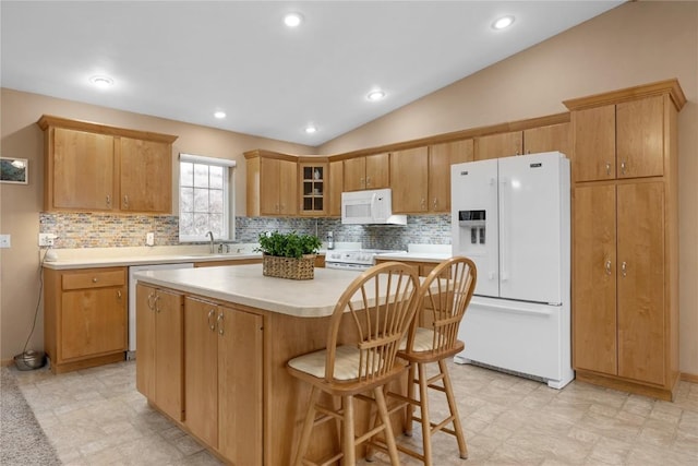 kitchen featuring a center island, lofted ceiling, light countertops, a sink, and white appliances