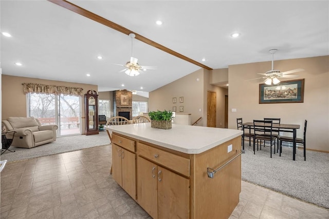 kitchen with a fireplace, light countertops, open floor plan, vaulted ceiling, and a kitchen island