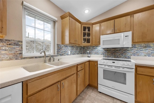 kitchen featuring white appliances, light countertops, a sink, and decorative backsplash