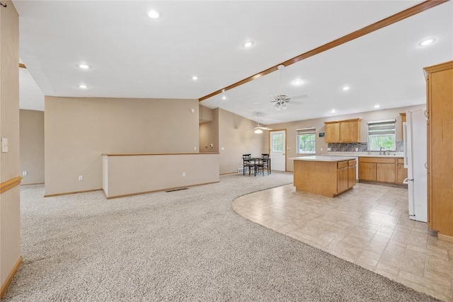 kitchen with a center island, baseboards, vaulted ceiling, and light colored carpet