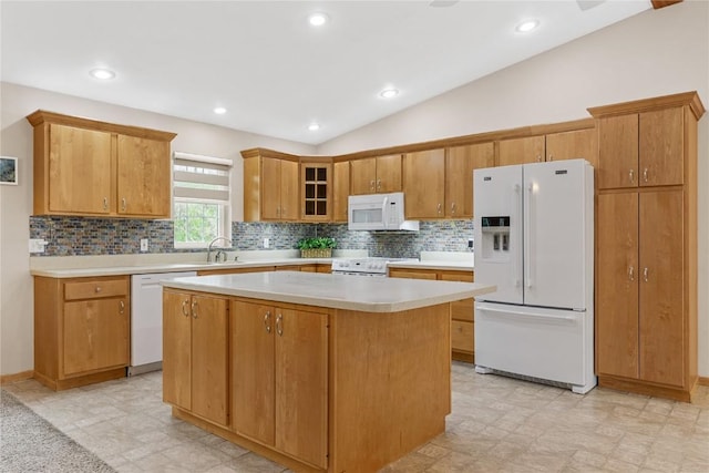kitchen with lofted ceiling, a kitchen island, white appliances, light countertops, and tasteful backsplash