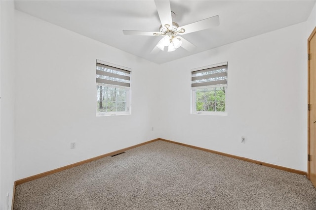 carpeted empty room with baseboards, plenty of natural light, a ceiling fan, and visible vents