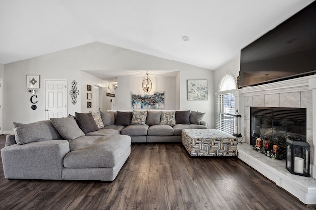 living room featuring vaulted ceiling, dark wood-type flooring, and a tile fireplace