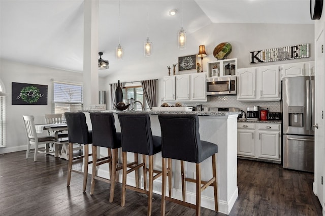 kitchen featuring white cabinets, appliances with stainless steel finishes, a breakfast bar, and dark wood finished floors