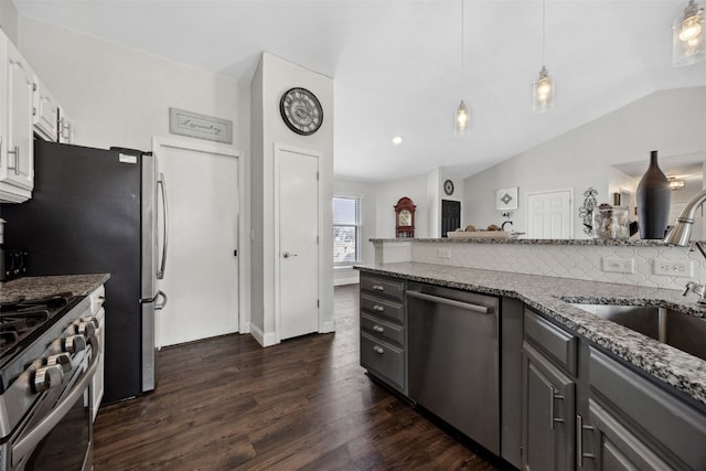 kitchen featuring dark wood-type flooring, light stone countertops, vaulted ceiling, stainless steel appliances, and pendant lighting