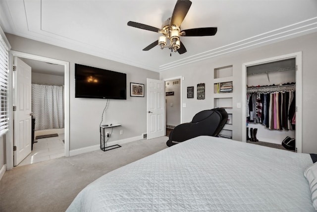 bedroom with baseboards, a ceiling fan, light colored carpet, ensuite bath, and a closet