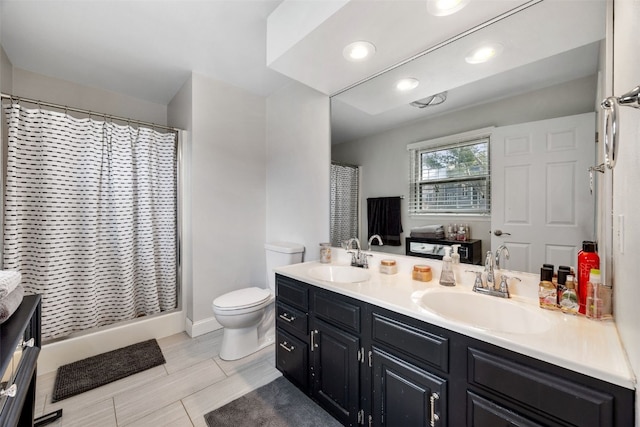 full bath featuring a shower with shower curtain, a sink, toilet, and double vanity