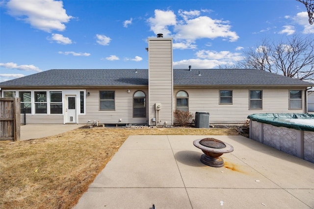 rear view of property with a patio, a chimney, central AC unit, an outdoor fire pit, and a covered pool