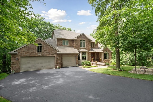 view of front of house featuring a shingled roof, brick siding, driveway, and a garage