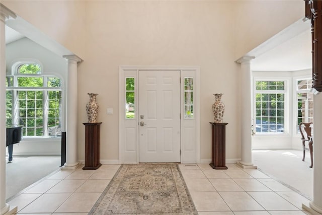 entrance foyer with a wealth of natural light, light tile patterned flooring, and decorative columns