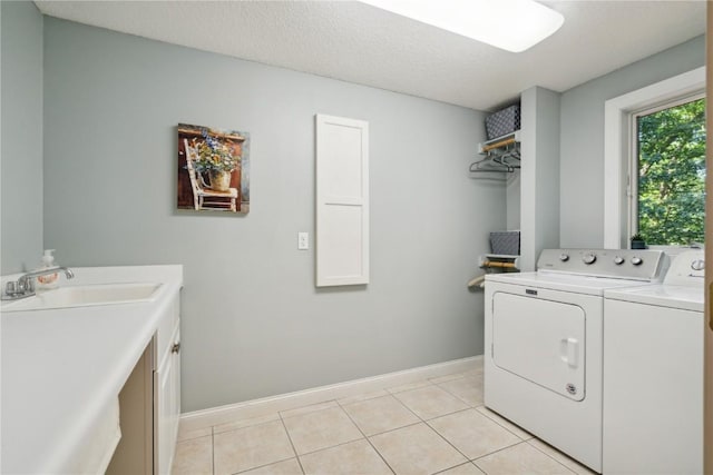 laundry room featuring light tile patterned floors, a sink, baseboards, cabinet space, and washer and clothes dryer