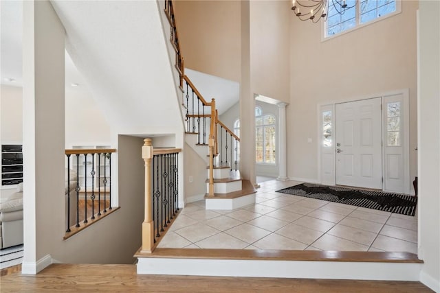 tiled entrance foyer featuring a towering ceiling, baseboards, and a wealth of natural light