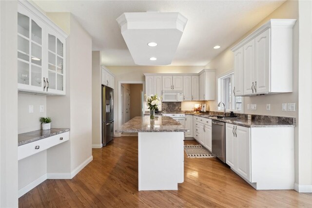 kitchen featuring appliances with stainless steel finishes, light wood-type flooring, white cabinets, and a kitchen island