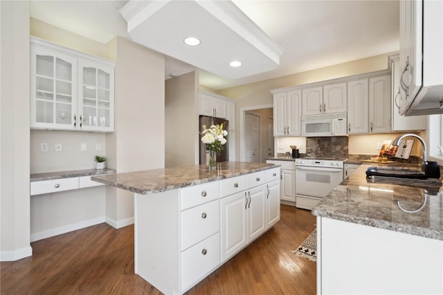 kitchen with dark wood-type flooring, glass insert cabinets, white cabinetry, a kitchen island, and white appliances