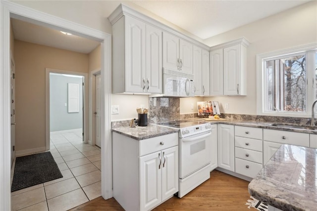 kitchen featuring light stone counters, white appliances, white cabinetry, and a sink