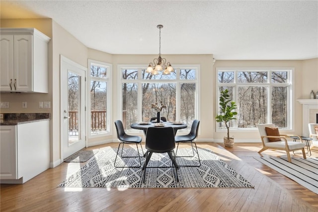 dining room featuring light wood-type flooring, an inviting chandelier, baseboards, and a textured ceiling