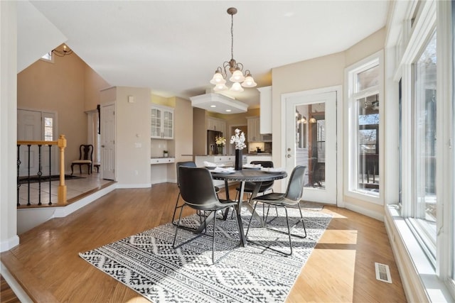 dining room with light wood-type flooring, an inviting chandelier, plenty of natural light, and baseboards