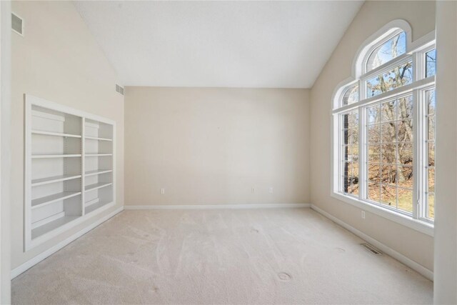 carpeted empty room featuring a healthy amount of sunlight, baseboards, and vaulted ceiling