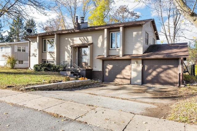 bi-level home with a garage, driveway, and a chimney