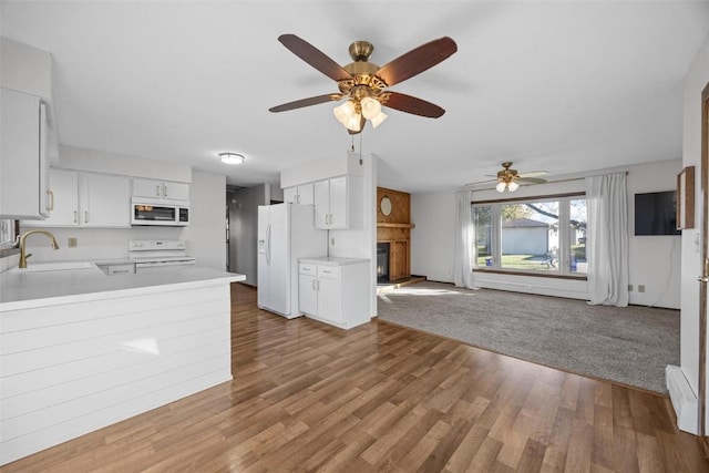 kitchen featuring open floor plan, light countertops, a peninsula, white appliances, and a sink