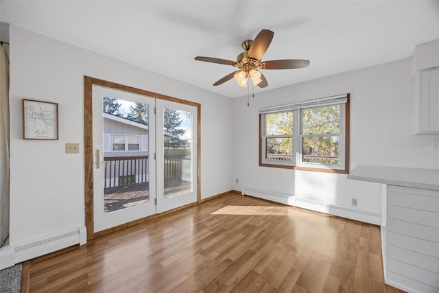 unfurnished dining area with light wood-type flooring, a baseboard heating unit, ceiling fan, and a baseboard radiator