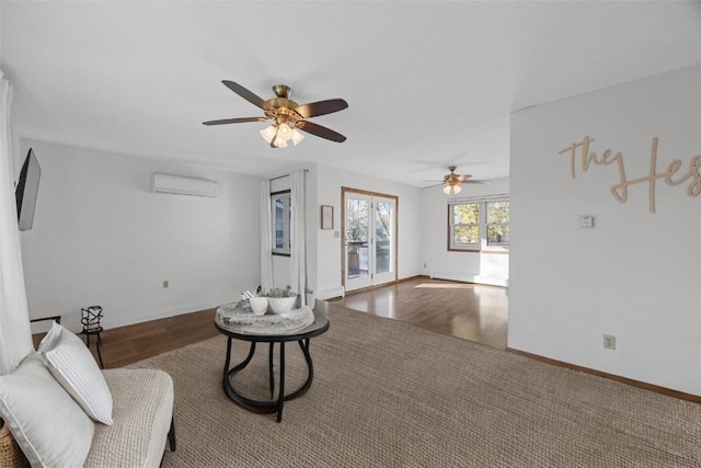 living room featuring baseboards, an AC wall unit, and wood finished floors