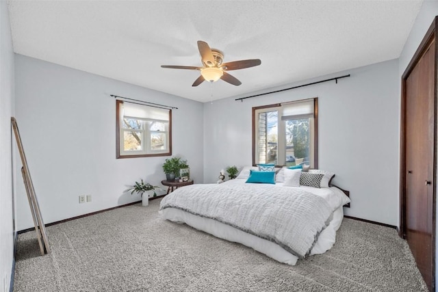 carpeted bedroom with a closet, baseboards, a textured ceiling, and ceiling fan