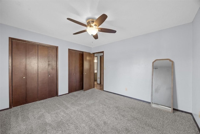 unfurnished bedroom with baseboards, carpet, multiple closets, and ceiling fan