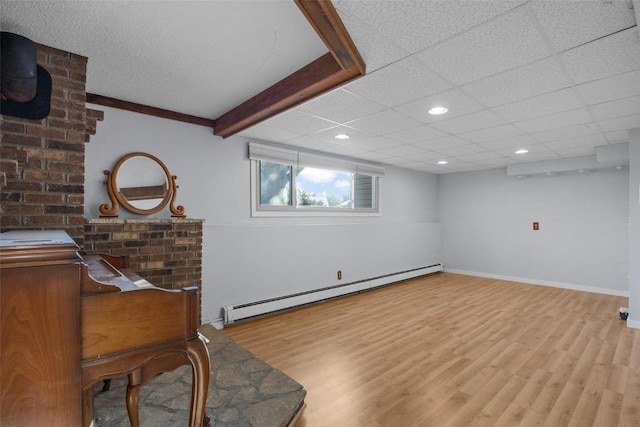 interior space with wood finished floors, baseboards, recessed lighting, a drop ceiling, and a baseboard heating unit