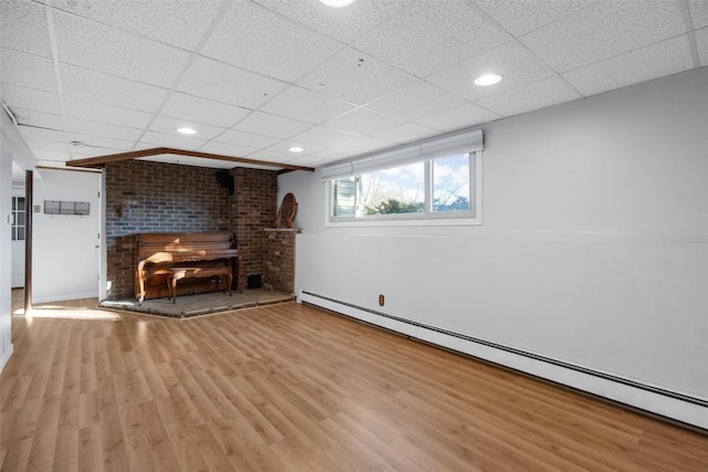 unfurnished living room featuring recessed lighting, baseboard heating, a drop ceiling, and wood finished floors