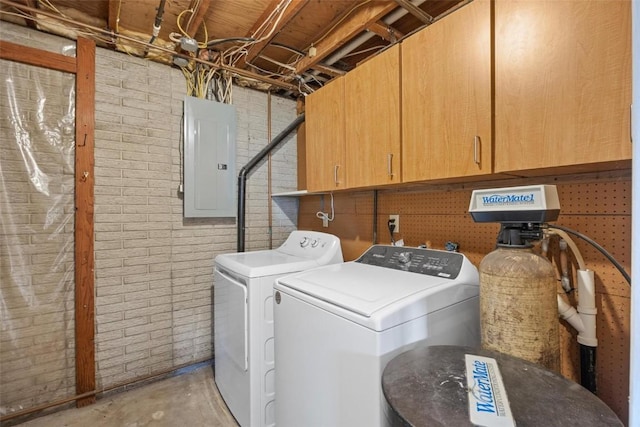 washroom with cabinet space, electric panel, washing machine and dryer, and brick wall