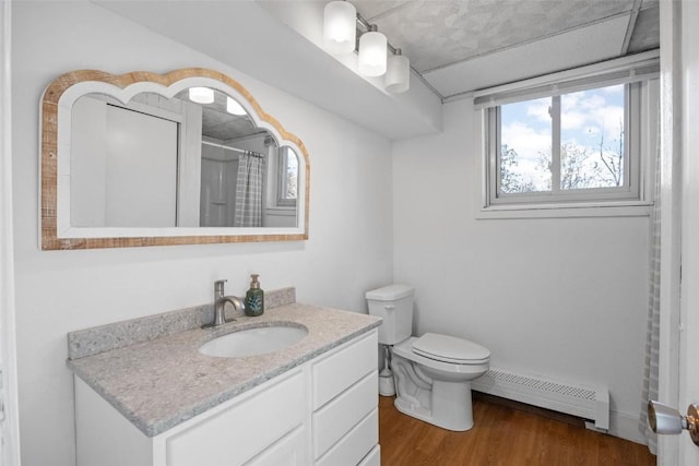 full bath with a baseboard heating unit, toilet, a shower with shower curtain, wood finished floors, and vanity