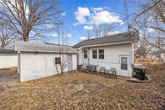 back of house featuring a garage, a chimney, and cooling unit