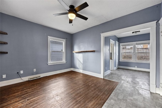 unfurnished room featuring visible vents, a ceiling fan, a textured ceiling, wood finished floors, and baseboards