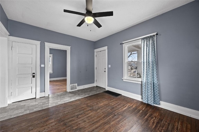 spare room with hardwood / wood-style flooring, visible vents, baseboards, and a ceiling fan