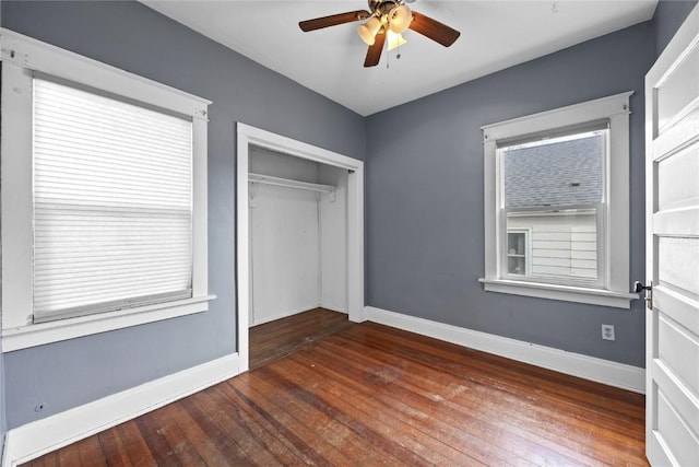 unfurnished bedroom with a ceiling fan, a closet, hardwood / wood-style floors, and baseboards