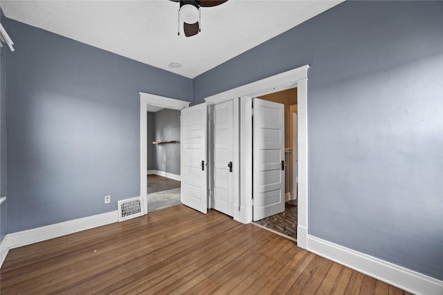 unfurnished bedroom with ceiling fan, wood-type flooring, visible vents, and baseboards