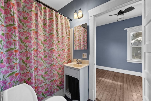 bathroom with ceiling fan, toilet, vanity, baseboards, and wood-type flooring