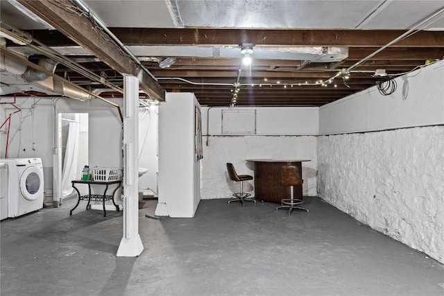 unfinished basement with a bar and washing machine and clothes dryer