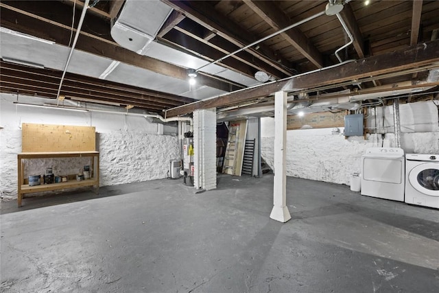 unfinished basement with water heater, washing machine and dryer, and electric panel