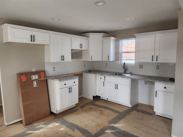 kitchen with white cabinets, decorative backsplash, a sink, and recessed lighting