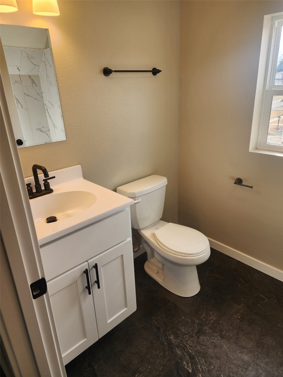 bathroom featuring toilet, baseboards, and vanity