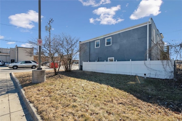 view of side of home with fence and stucco siding