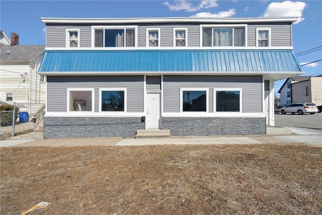 back of house featuring fence and metal roof