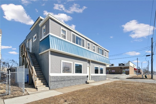 exterior space with stone siding, stairway, fence, and stucco siding