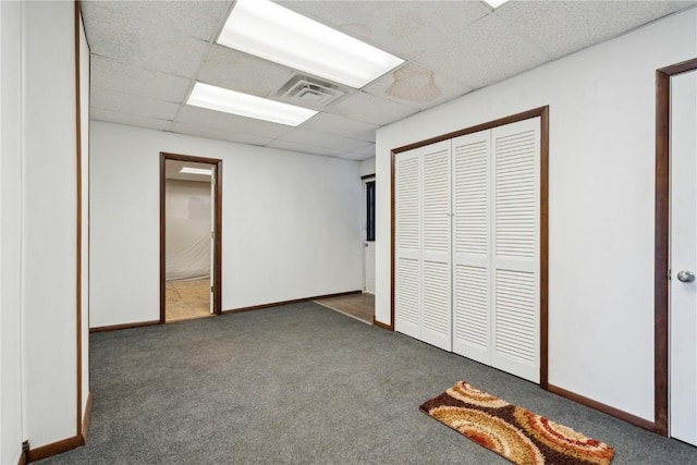 unfurnished bedroom with carpet floors, baseboards, visible vents, and a drop ceiling